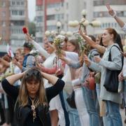 En kvinna i Minsk står på knä samtidigt som demonstranter bildar mänskliga kedjor i protest mot regimen.