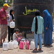 En familj som fördrivits från sitt hem fyller dunkar med vatten i Gaza stad.