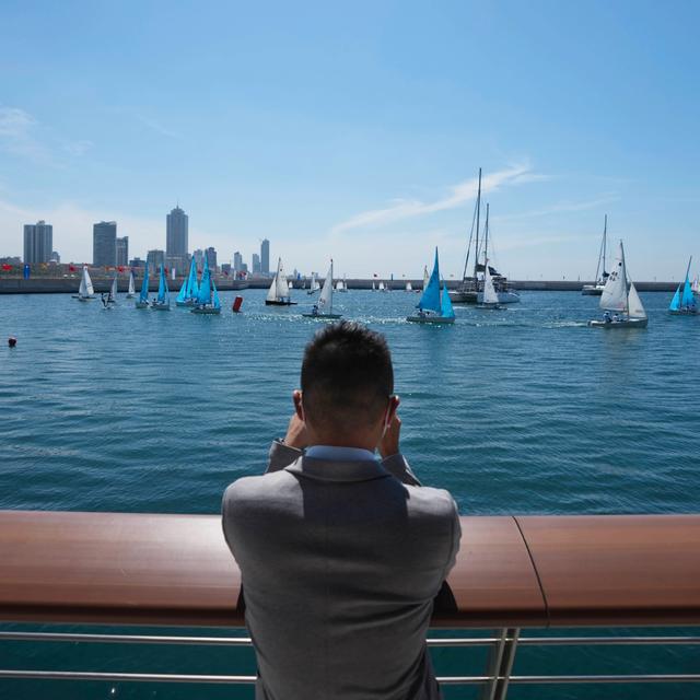 A Chinese national who lives in Sri Lanka photographs the surroundings of Chinese funded sea reclamation Port City project during a ceremony held to mark the visit of Chinese Foreign Minister Wang Yi in Colombo, Sri Lanka, Sunday, Jan. 9, 2022. Eranga Jayawardena / AP