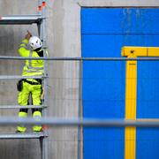 Arkivbild: En man in hjälm och skyddskläder monterar byggställning i bygget av nya bostadsområdet Haga Norra. 