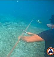 Filippinsk kustbevakning skär av rep som håller fast flytbarriären i Sydkinesiska havet. AP