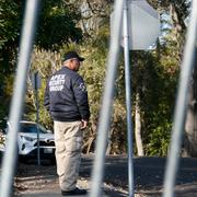 En vakt står bakom staketet som inhägnar FTX-grundaren Sam Bankman-Frieds föräldrahem, där han befinner sig släppt mot borgen i väntan på rättegång. 