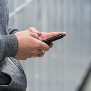 En ung person med sin mobil i skolmiljö. Arkivbild. 