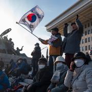 En demonstrant viftar med en sydkoreansk flagga utanför nationalförsamlingen i Seoul, 4 december 2024.