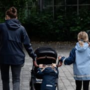 Mamma med två barn på promenad.