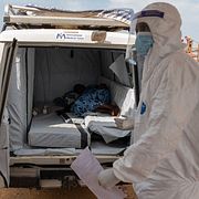 En sjukvårdare står vid en ambulans lastad med en ebola-patient.