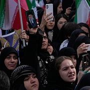 En kvinna visar upp ett porträtt av Irans tidigare högste ledare ayatolla Ali Khamenei vid en minnesplats i centrala Teheran för skolbarn som dödades i en attack mot en skola i den sydliga staden Minab den 28 februari.