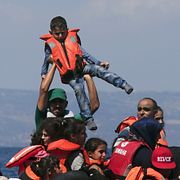 Man lyfter pojke efter att luften gått ur en gummibåt hundratals meter från Lesbos