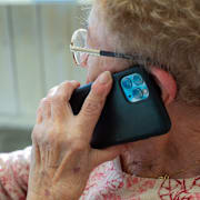 Äldre kvinna pratar i mobiltelefon.