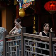  People wait outside a restaurant in Beijing, Tuesday, Aug. 15, 2023.