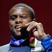 Christian Coleman biter i sin guldmedalj han fick 2019. 