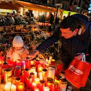 Barn och vuxna placerar ljus utanför baren Le Constellation. 