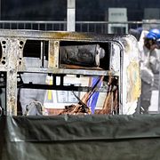 Utredare genomsöker skalet av den utbrända bussen.