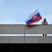 En man med Slovakiens flagga utanför sjukhuset där Robert Fico vårdas.