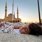 En pojke som befinner sig på flykt med sin familj sover på gatan i Beirut.