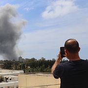En man fotograferar en rökpelare efter en israelisk attack mot den libanesiska staden Tyr.