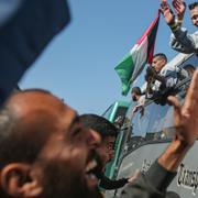 Palestinier vinkar från den buss som transporterat dem in i Gaza för att friges på lördagen. 