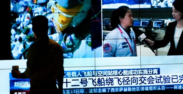Kinesisk tv visar bilder på taikonauterna inuti rymdfarkosten på väg tillbaka till jorden.  Andy Wong / TT NYHETSBYRÅN