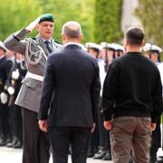 En tysk soldat hälsar på Olaf Scholz och Volodymyr Zelenskyj i Berlin den 14 maj 2023.