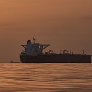 Solen går upp bakom oljetankers som ligger för ankar i Hormuzsundet.