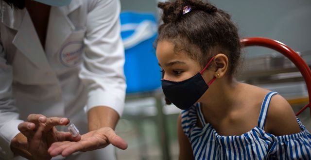 En kubansk flicka får titta på ampullen med vaccinet Soberana 02. Hon fick sin första vaccindos i augusti 2021.  Ramon Espinosa / AP