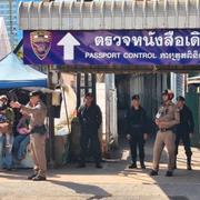 Thailändsk polis talar med människor vid en gränskontroll i Thailand. 
