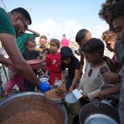 Barn på flykt får mat i ett läger i Gaza.