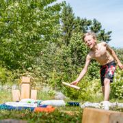 Arkivbild på barn som spelar kubb i trädgård på sommaren.