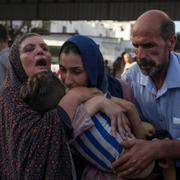 En kvinna bär sin 6-åriga son. Han dog i en israelisk attack under lördagen den 12 juli. 
