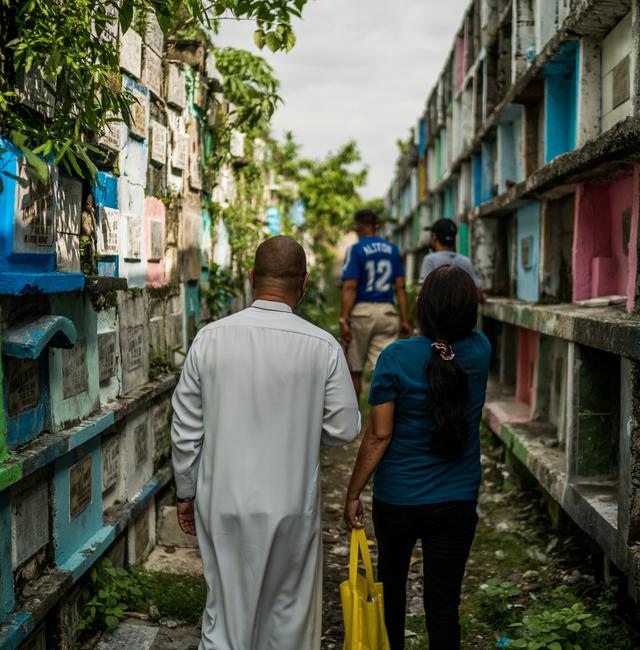The Rev. Flaviano Villanueva walks with Janelle "Gemma" Angeles Gallon, widow of Patricio Baran, at Tala Cemetery in Caloocan City, north of Manila. Martin San Diego / For The Washington Post