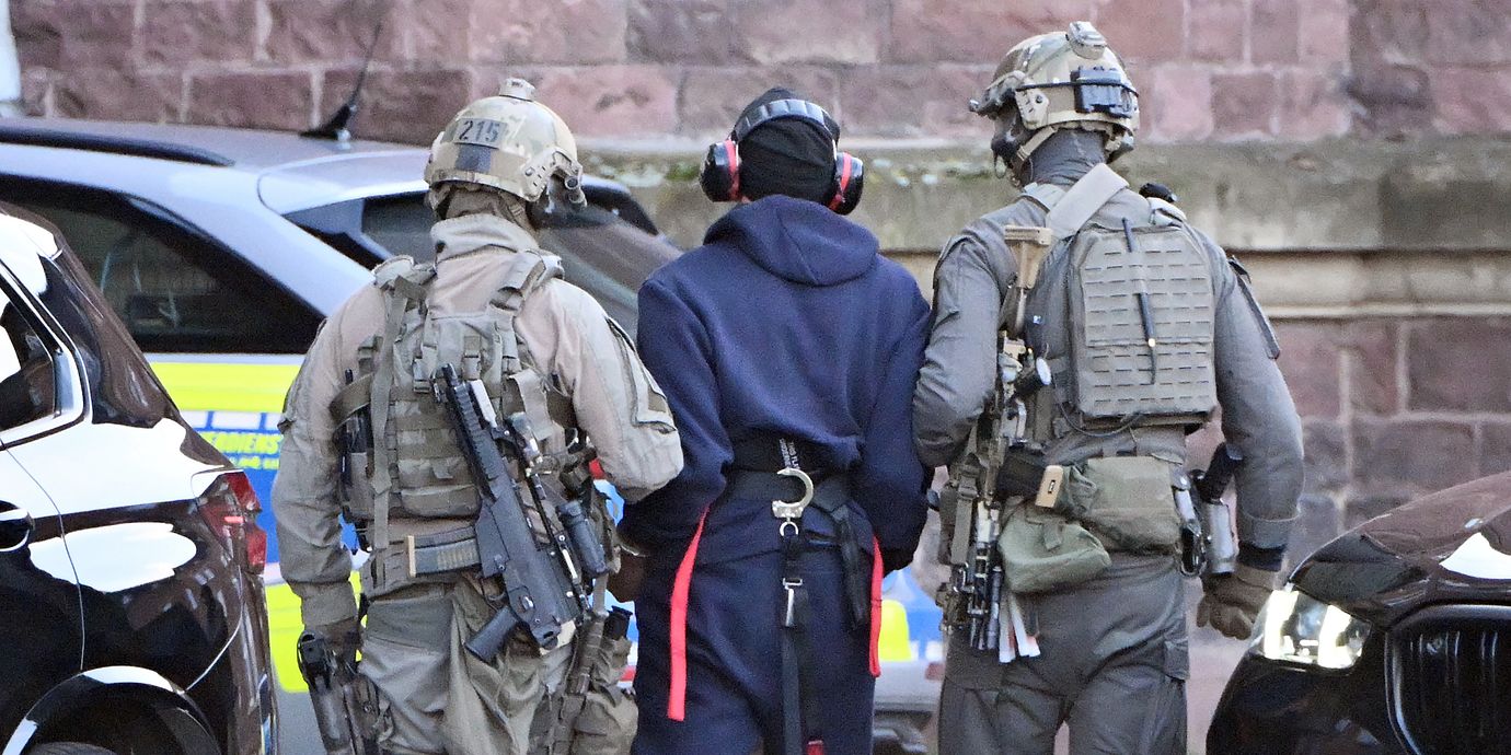 Den misstänkte mannen leds av polis.