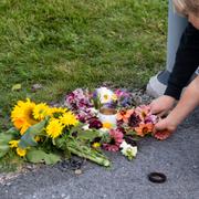 Blommor läggs i vägkorsningen nedanför de förstörda radhusen utanför Uppsala efter detonationen i veckan.