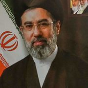 En kvinna håller upp ett porträtt av Mojtaba Khamenei.