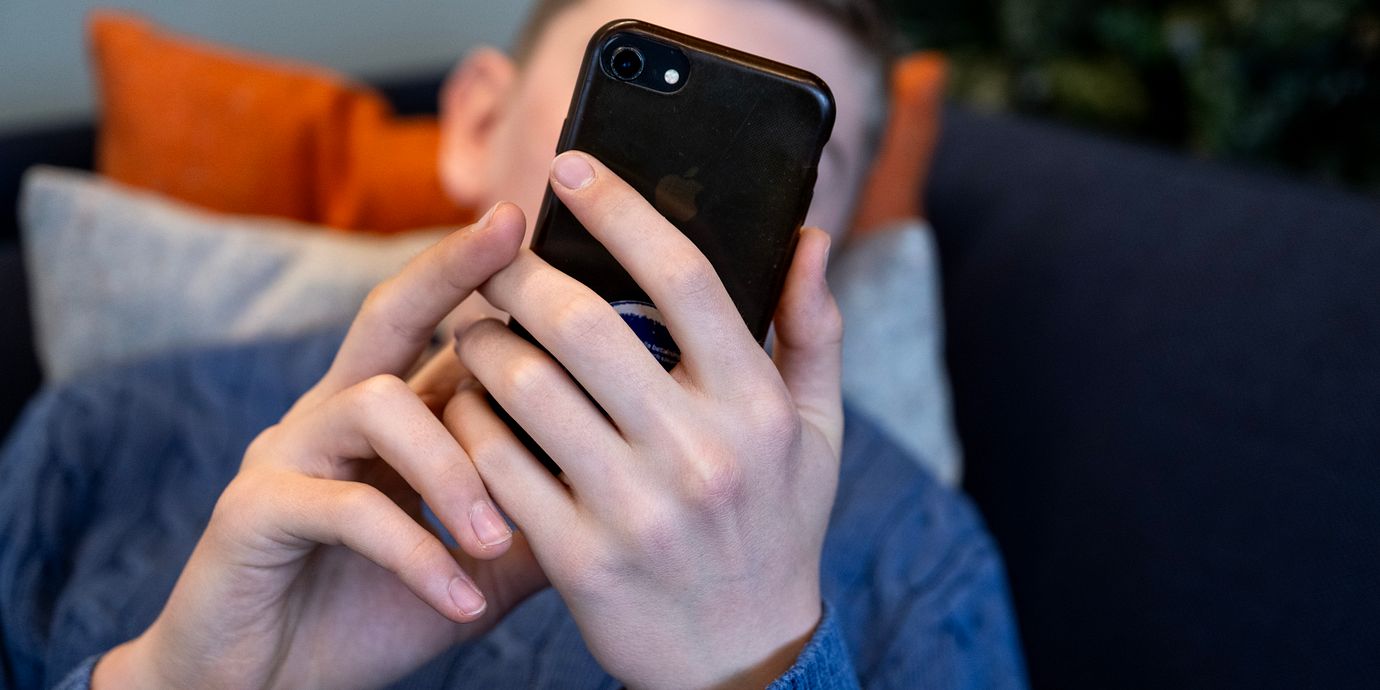 Illustrationsbild. En ung kille med mobiltelefon.