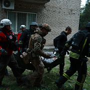 Räddningsarbetare i Zaporizjzja för bort en skadad kvinna efter en rysk attack mot ett flerfamiljshus i helgen.