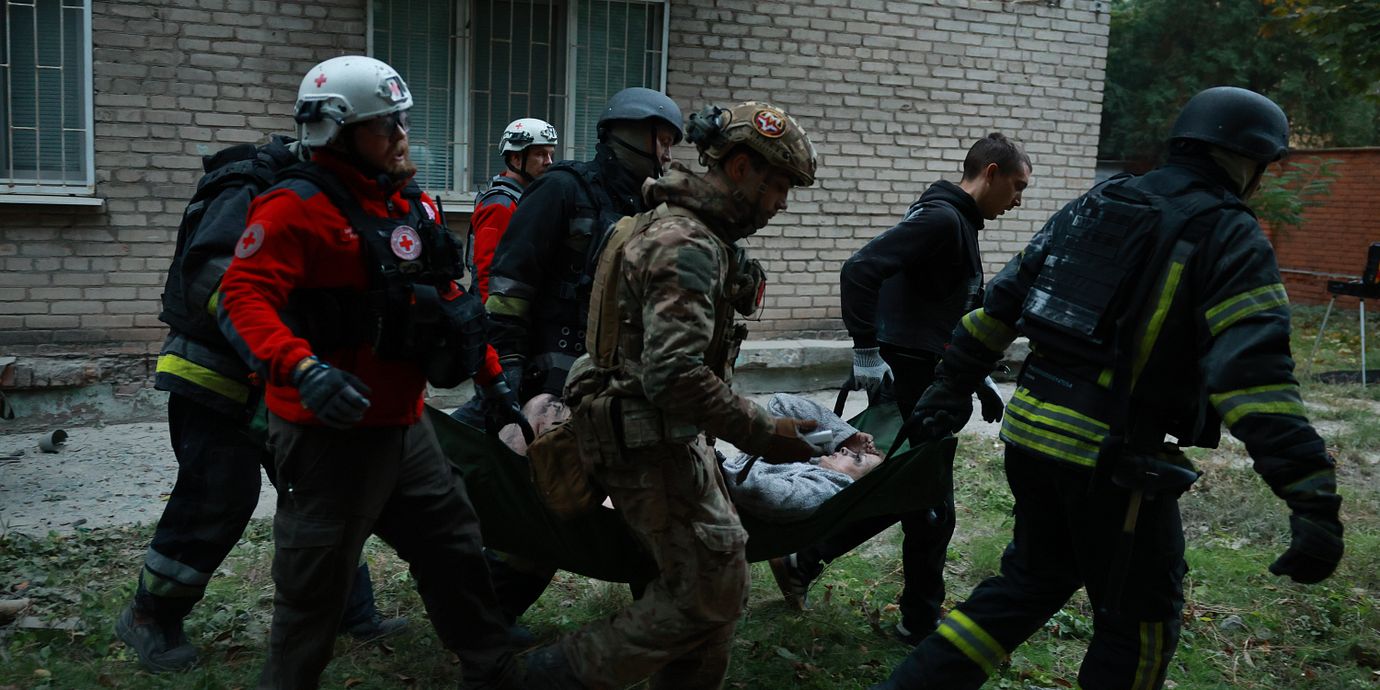 Räddningsarbetare i Zaporizjzja för bort en skadad kvinna efter en rysk attack mot ett flerfamiljshus i helgen.