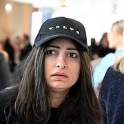 Vänsterpartiets ledare Nooshi Dadgostar (V) utanför plenisalen i Volvo-keps.