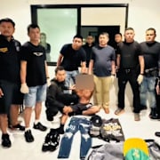 Den gripne 39-åringen omgärdad av polis på en bild som släppts av Phukets regionala polis.