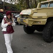 En kvinna kollar sin telefon samtidigt som hon passerar ett militäfrodon p Tajrish-torget i Teheran.