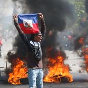 En demonstrant håller upp Haitis flagga i huvudstaden Port-au-Prince.