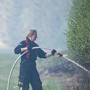 En brandman i arbete. Till höger en skärmdump från SMHI:s varningskarta.