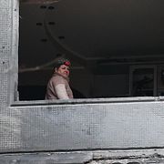 En kvinna tittar ut genom sitt trasiga fönster efter en rysk drönarattack mot ett bostadshus i Zaporizjzja, Ukraina den 26 februari 2026.