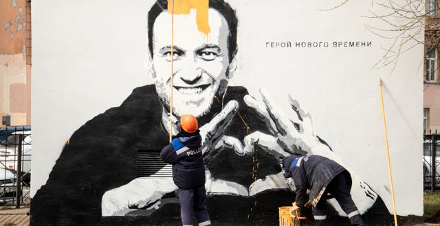 Renhållningsarbetare målar över en målning av Aleksej Navalnyj i Moskva.  Ivan Petrov / TT NYHETSBYRÅN