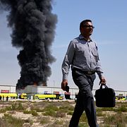 En man går iväg från en brinnande lagerlokal i Förenade Arabemiraten efter en iransk attack.