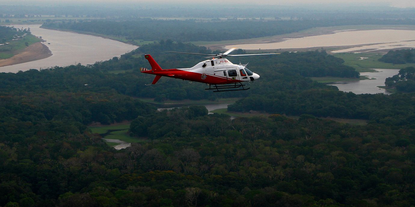 En helikopter flyger över Amazonas regnskog i Brasilien.