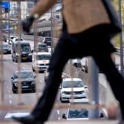 En man passerar på Riddarholmsbron. Under bron passerar tät trafik på Centralbron.