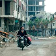 Arkivbild:  Syrian man drives past destroyed buildings in Arbin on December 18, 2018.