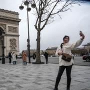 En turist tar en selfie i centrala Paris.