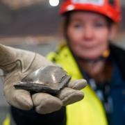 Susanne Rostmark, forskningsledare på LKAB, håller ett stycke järnbrikett från HYBRIT-processen vid pilotanläggningen i Luleå.