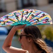 En kvinna i Madrid försöker skydda sig från solen med en solfjäder.  Manu Fernandez / AP